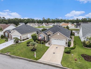 View of front of property with concrete driveway, an attached garage, a residential view, and a front yard