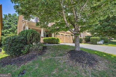 View of property hidden behind natural elements featuring concrete driveway, brick siding, and a garage