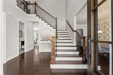 Foyer featuring a towering ceiling, wood finished floors, stairs, and baseboards