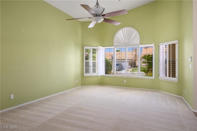 Carpeted empty room featuring high vaulted ceiling