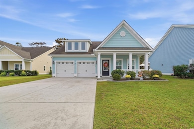 View of front of house with covered porch, a shingled roof, a front yard, driveway, and a garage