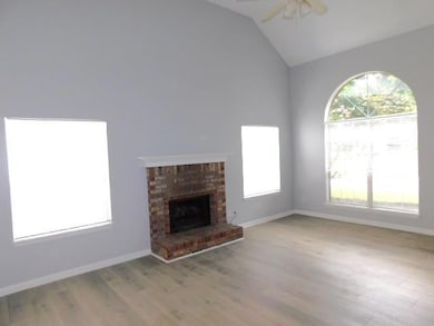 Unfurnished living room featuring ceiling fan, wood finished floors, lofted ceiling, and a fireplace