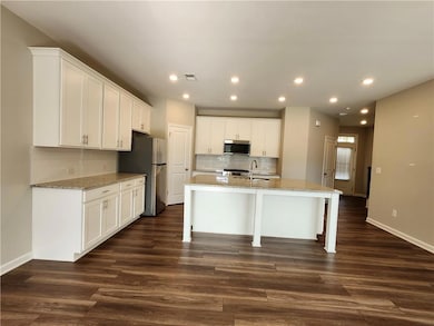 Kitchen with stainless steel appliances, white cabinets, decorative backsplash, and recessed lighting