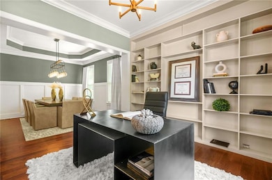 Office space with dark wood-style floors, a notable chandelier, and ornamental molding