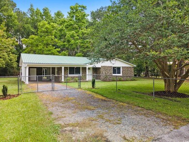 Single story home featuring a gate, driveway, ston