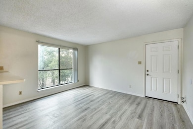 Unfurnished living room featuring light wood-type flooring and a textured ceiling