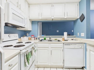Kitchen with white appliances, a sink, and light 