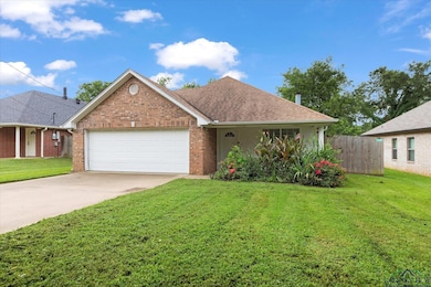 View of front facade featuring a garage, driveway, brick siding, and roof with shingles