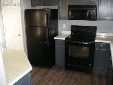 Kitchen with black appliances and dark hardwood / 