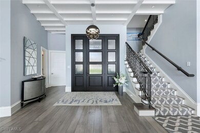 Foyer entrance featuring stairs, beam ceiling, a towering ceiling, wood finished floors, and coffered ceiling
