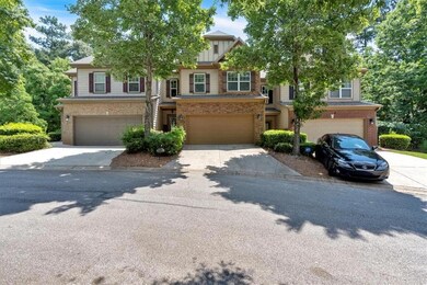View of property featuring an attached garage, concrete driveway, and brick siding