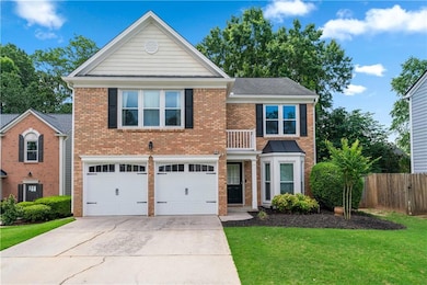 View of front of home featuring a balcony, driveway, brick siding, and a garage