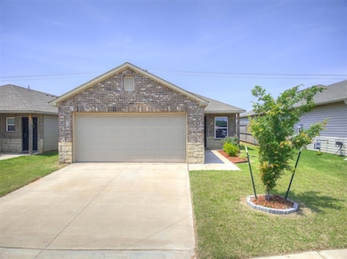 Single story home featuring brick siding, concrete driveway, a front yard, an attached garage, and roof with shingles