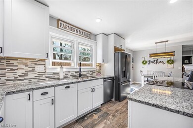 Kitchen featuring hanging light fixtures, sink, stainless steel appliances, and white cabinetry