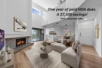 Living area with plenty of natural light, wood finished floors, a towering ceiling, and a fireplace