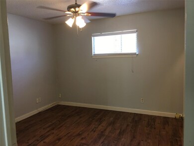 Unfurnished room featuring a ceiling fan, dark wo