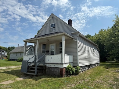 View of side of home with a front lawn, a porch, and a chimney