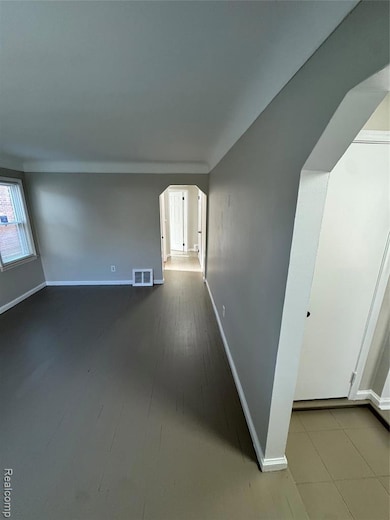 Empty room featuring arched walkways and dark wood-style flooring