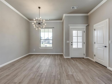 Foyer featuring healthy amount of natural light, crown molding, a chandelier, and light wood-type flooring