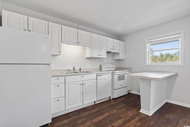 Kitchen with white appliances, white cabinets, and light countertops