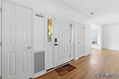 Foyer featuring healthy amount of natural light, crown molding, and wood finished floors