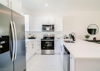 Kitchen with appliances with stainless steel finishes, white cabinetry, a peninsula, light stone countertops, and recessed lighting