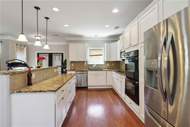 Kitchen featuring stainless steel appliances, crown molding, tasteful backsplash, white cabinetry, and pendant lighting