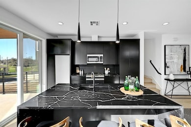 Kitchen with dark cabinetry, stainless steel microwave, decorative backsplash, a sink, and recessed lighting