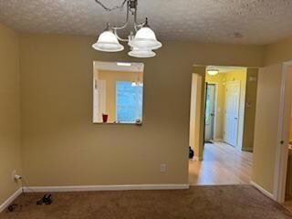 Carpeted spare room with an inviting chandelier an