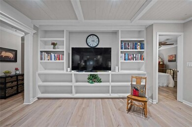 Living area with built in features, wood finished floors, ornamental molding, and a wooden ceiling with exposed beams