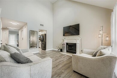 Living area featuring a towering ceiling, light wood-style flooring, and a fireplace with flush hearth