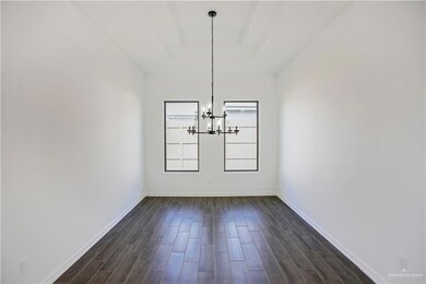 Unfurnished dining area with baseboards, dark wood-style floors, an inviting chandelier, and a raised ceiling