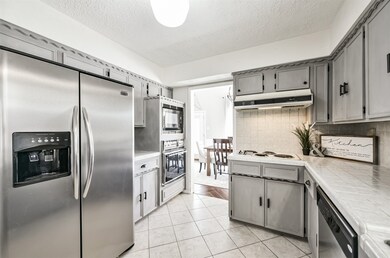 Step into the kitchen to find stylish grey paint to update the original solid wood cabinetry, classic white tile countertops and backsplash, and easy-to-maintain ceramic tile floors.