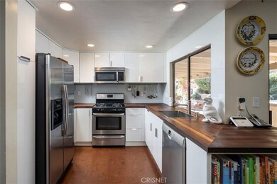 solid Boos block countertops throughout, cut glass backsplash, stainless appliances, and more storage than you can see all lend to the beauty of this modern kitchen