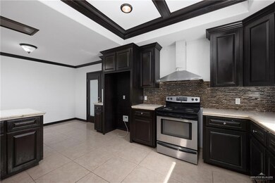 Kitchen featuring wall chimney range hood, backsplash, stainless steel range with electric cooktop, and light tile floors