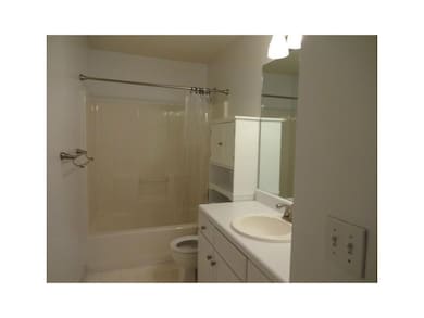 Bathroom with toilet, vanity, and shower / tub combo with curtain
