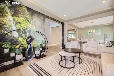 Sitting area with light wood-style floors, a chandelier, recessed lighting, and a tray ceiling