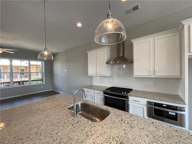 Kitchen with a sink, stainless steel appliances, white cabinetry, decorative backsplash, and light stone counters