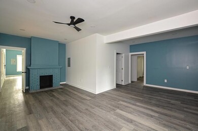 Unfurnished living room featuring a ceiling fan, dark wood finished floors, and a fireplace