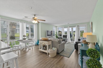 Living area with plenty of natural light, wood finished floors, a ceiling fan, and a textured ceiling
