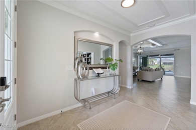 Hall with an inviting chandelier, ornamental molding, and light tile patterned flooring