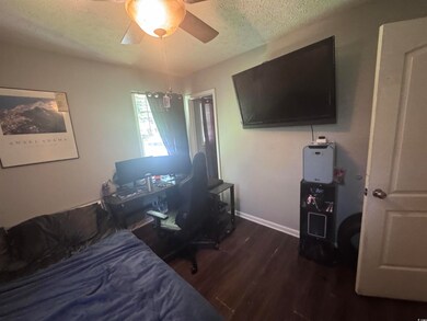 Bedroom with a textured ceiling, wood finished floors, a ceiling fan, baseboards, and a desk