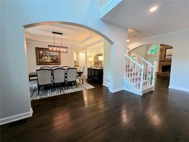 Foyer with arched walkways, french doors, crown molding, wood finished floors, and healthy amount of natural light