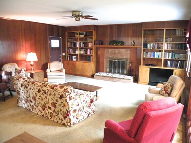 large living room with fireplace with large windows that give lots of light. 