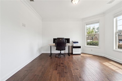 Office space featuring visible vents, crown molding, baseboards, and dark wood-style flooring