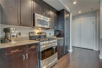 Close up of range & microwave. Note the full cabinet at the end that houses the pantry.  The white double doors lead to the washer/dryer.