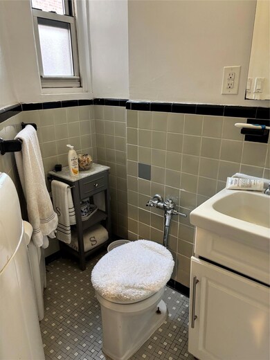 Bathroom featuring vanity, a wainscoted wall, and tile walls