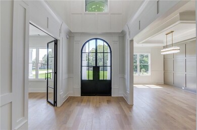 Foyer entrance featuring french doors, a tray ceiling, light wood-type flooring, and a notable chandelier