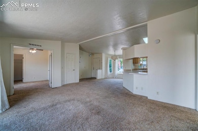Unfurnished living room with carpet flooring, a textured ceiling, and ceiling fan