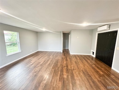 Unfurnished living room featuring dark wood finished floors and a wall mounted air conditioner